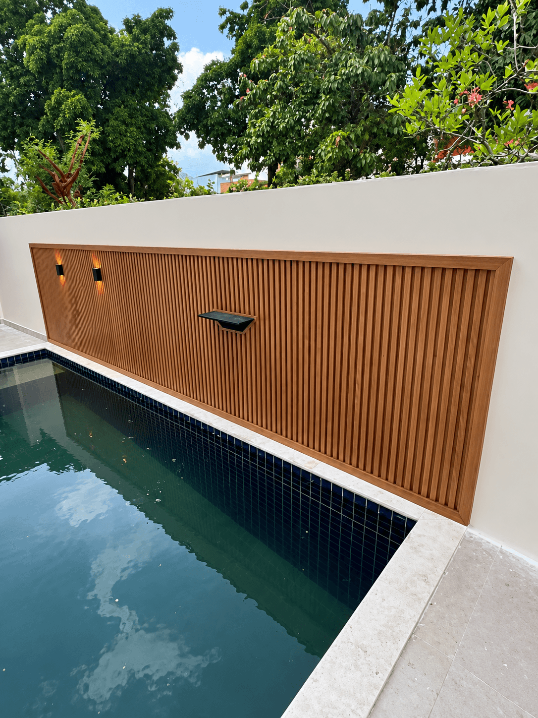 Piscina ao lado de parede com revestimento ripado de madeira